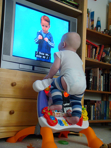 James climbing onto his toy to look at the TV